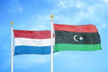 Hollanda ve Libya bayrak direkleri ve mavi bulutlu arka planda iki bayrak
