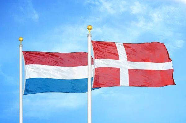 オランダとデンマークの旗竿と青空の背景に2つの旗 — ストック写真