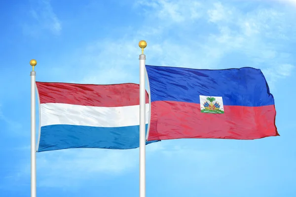 オランダとハイチの旗竿と青空の背景に2つの旗 — ストック写真