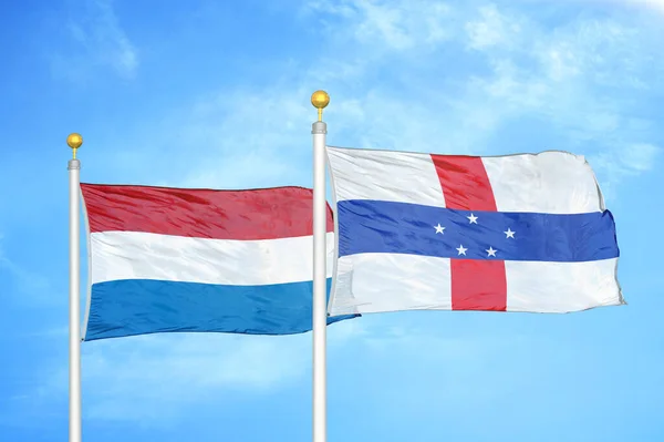 Netherlands and Netherlands Antilles two flags on flagpoles and blue cloudy sky background