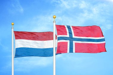 Hollanda ve Norveç bayrak direkleri ve mavi bulutlu arka planda iki bayrak