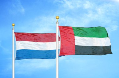 Hollanda ve Birleşik Arap Emirlikleri bayrak direkleri ve mavi bulutlu arka planda iki bayrak