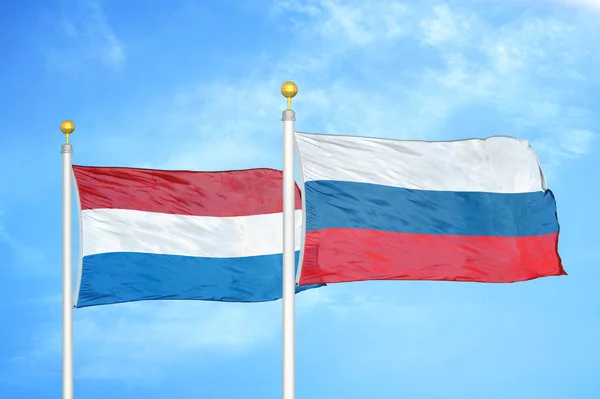 オランダとロシアの旗竿と青空の背景に2つの旗 — ストック写真