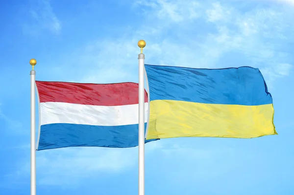 オランダとウクライナの旗竿と青空の背景に2つの旗 — ストック写真