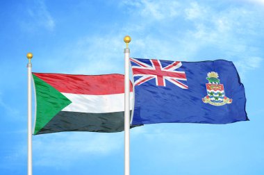 Sudan ve Cayman Adaları bayrak direkleri ve mavi bulutlu arka planda iki bayrak