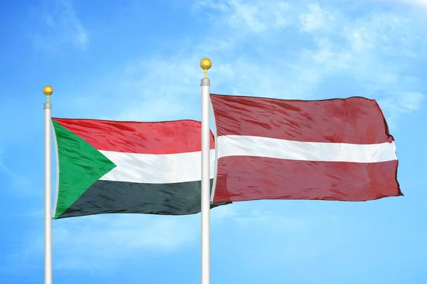 Sudan Łotwa Dwie Flagi Maszcie Flagowym Niebieskie Zachmurzone Tło Nieba — Zdjęcie stockowe