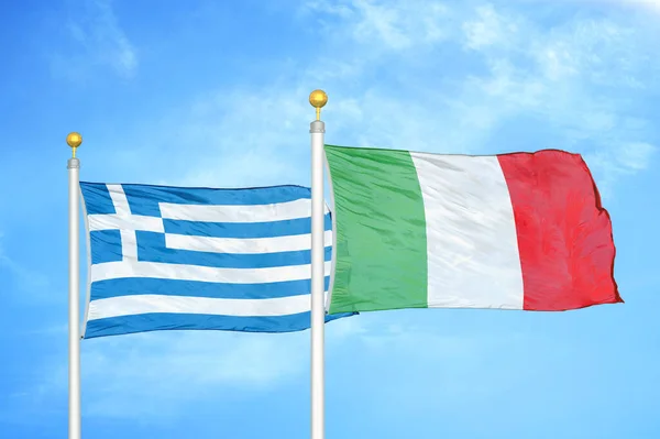 Greece and Italy two flags on flagpoles and blue cloudy sky background