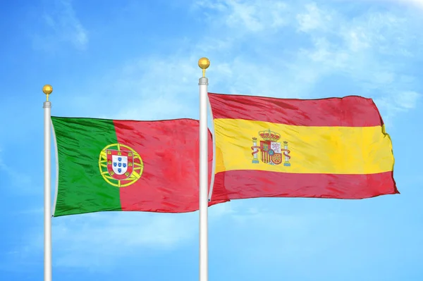葡萄牙和西班牙旗杆上的两面旗帜和蓝云的天空背景 — 图库照片