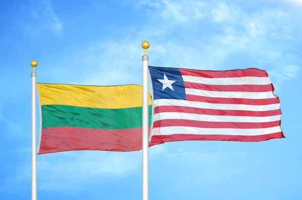 リトアニアとリベリアの旗竿と青空の背景に2つの旗 — ストック写真