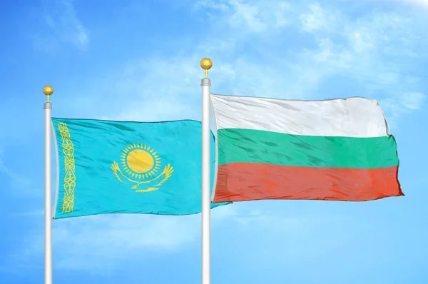 Kazakhstan and Bulgaria two flags on flagpoles and blue cloudy sky background