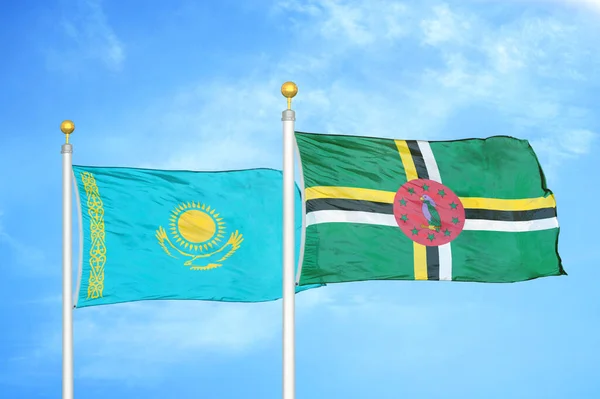 Kazakhstan and Dominica two flags on flagpoles and blue cloudy sky background