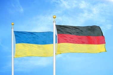Ukrayna ve Almanya bayrak direkleri ve mavi bulutlu arka planda iki bayrak