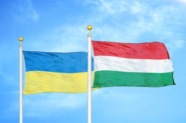 Ukrayna ve Macaristan bayrak direkleri ve mavi bulutlu arka planda iki bayrak