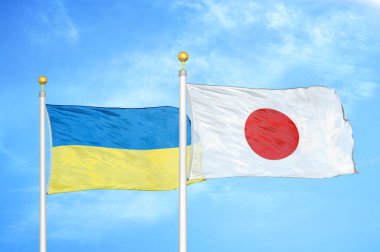 Ukrayna ve Japonya bayrak direkleri ve mavi bulutlu arka planda iki bayrak