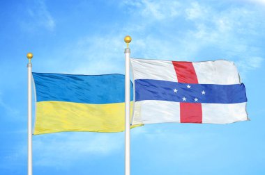 Ukrayna ve Hollanda Antilleri bayrak direkleri ve mavi bulutlu arka planda iki bayrak
