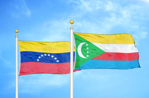 Venezuela and Comoros two flags on flagpoles and blue cloudy sky background