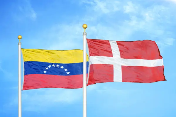 ベネズエラとデンマークの旗竿と青空の背景に2つの旗 — ストック写真