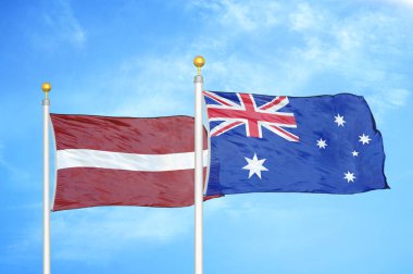 Letonya ve Avustralya bayrak direkleri ve mavi bulutlu arka planda iki bayrak