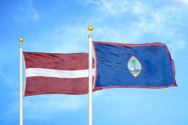 Letonya ve Guam bayrak direkleri ve mavi bulutlu arka planda iki bayrak