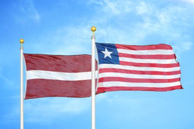 Letonya ve Liberya bayrak direkleri ve mavi bulutlu arka planda iki bayrak