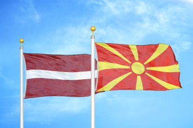 Letonya ve Kuzey Makedonya bayrak direkleri ve mavi bulutlu arka planda iki bayrak