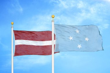 Letonya ve Mikronezya bayrak direkleri üzerinde iki bayrak ve mavi bulutlu gökyüzü arkaplanı