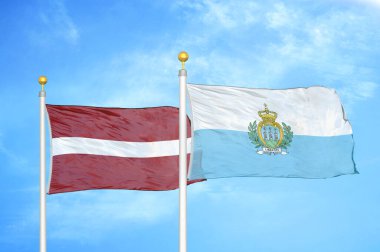 Letonya ve San Marino bayrak direkleri ve mavi bulutlu arka planda iki bayrak