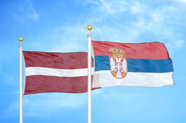 Letonya ve Sırbistan bayrak direkleri ve mavi bulutlu arka planda iki bayrak