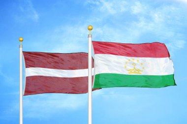 Letonya ve Tacikistan bayrak direkleri ve mavi bulutlu arka planda iki bayrak