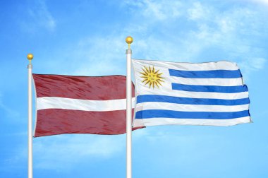Letonya ve Uruguay bayrak direkleri ve mavi bulutlu arka planda iki bayrak