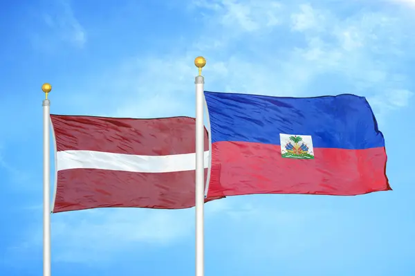 ラトビアとハイチの旗竿と青空の背景に2つの旗 — ストック写真