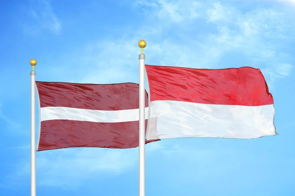 라트비아와 인도네시아 깃대와 구름낀 배경에 — 스톡 사진