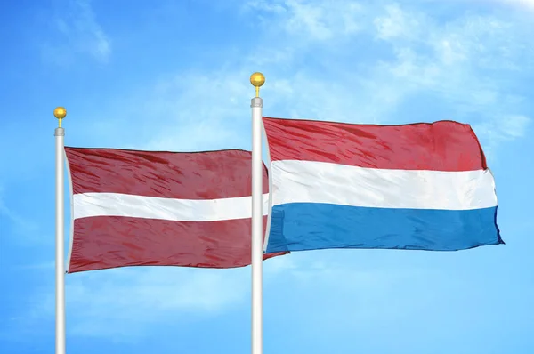 ラトビアとオランダの旗竿と青空の背景に2つの旗 — ストック写真