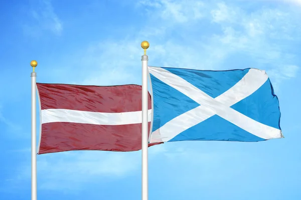 Lotyšsko Skotsko Dvě Vlajky Vlajkových Stožárech Modrá Oblačná Obloha Pozadí — Stock fotografie