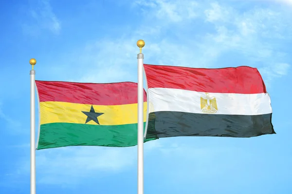 Ghana and Egypt two flags on flagpoles and blue cloudy sky background