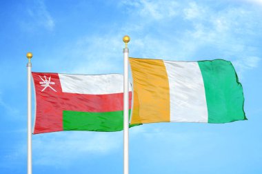 Umman ve Fildişi Fildişi Sahilleri bayrak direkleri ve mavi bulutlu arka planda iki bayrak