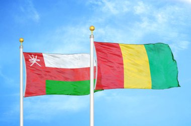 Umman ve Gine bayrak direğinde iki bayrak ve mavi bulutlu arka plan