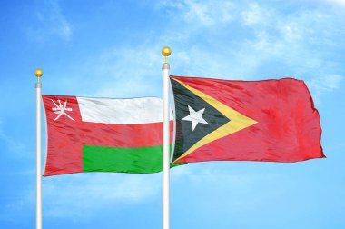 Umman ve Timor-Leste Doğu Timor bayrak direkleri üzerinde iki bayrak ve mavi bulutlu arka plan