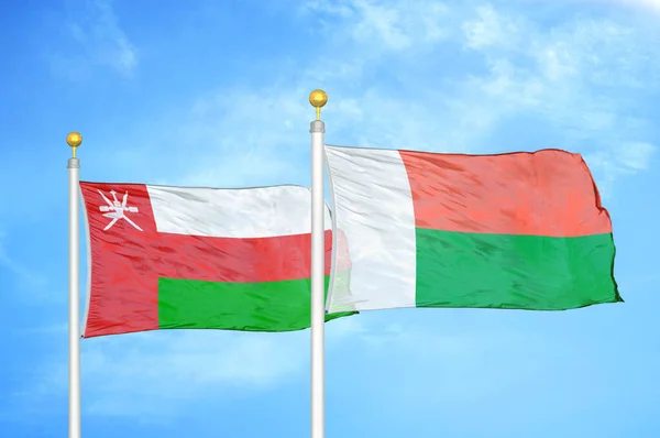 Oman Madagascar Deux Drapeaux Sur Mâts Fond Bleu Ciel Nuageux — Photo