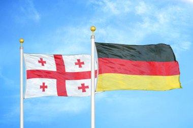 Gürcistan ve Almanya bayrak direkleri ve mavi bulutlu arka planda iki bayrak