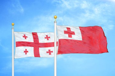 Georgia ve Tonga bayrak direkleri ve mavi bulutlu arka planda iki bayrak