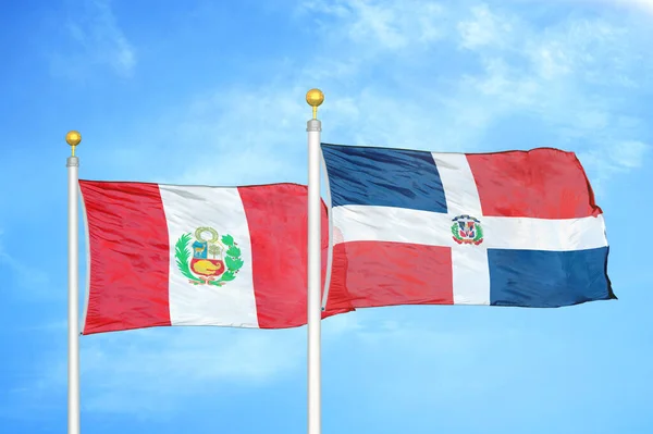 ペルーとドミニカ共和国の旗竿と青空の背景に2つの旗 — ストック写真