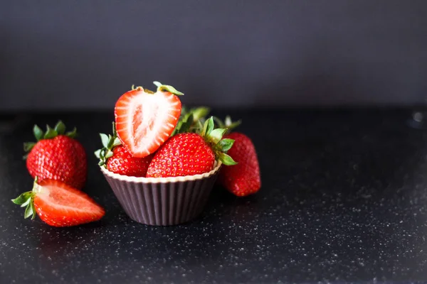 Olgun kırmızı çilek siyah bir zemin üzerine bir muffin sepeti