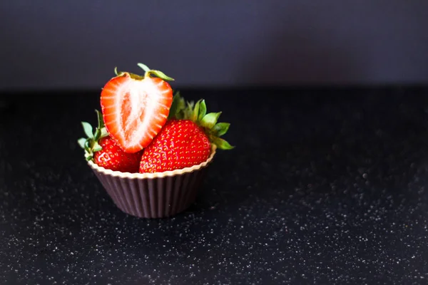 Olgun kırmızı çilek siyah bir zemin üzerine bir muffin sepeti