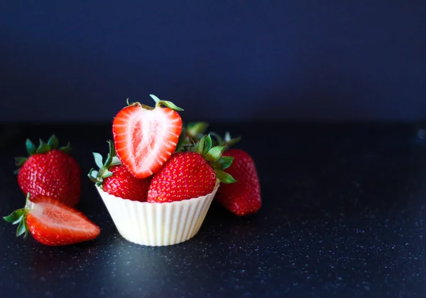 Olgun kırmızı çilek siyah bir zemin üzerine bir muffin sepeti