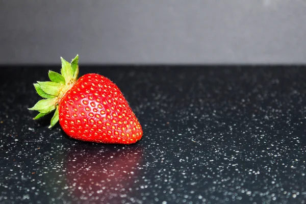Olgun kırmızı çilek siyah bir zemin üzerine