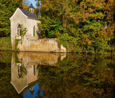 Dender Flanders Belçika nehri boyunca sonbahar ağaçlarında saklı küçük bir şapel.