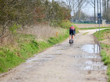 Yalnız bir bisikletçi güneşli bir günde çamurlu ve asfaltsız bir yolda yol alır. Sürücünün bu manzaralı off-road macerasında kararlılığı bellidir..