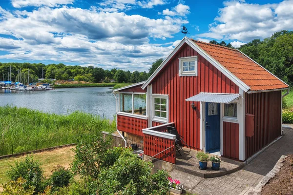 Casa de madera escandinava roja en el lago con hermoso cielo azul — Foto de Stock