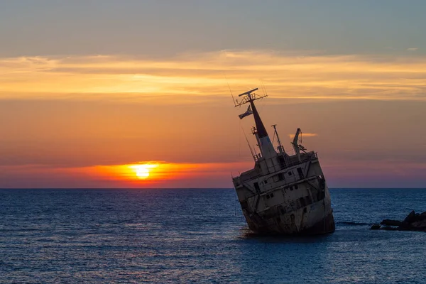 Picture ship wreck in the sea with sunset at the background